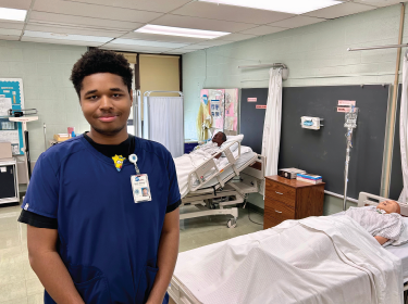 student smiling in a simulated hospital room